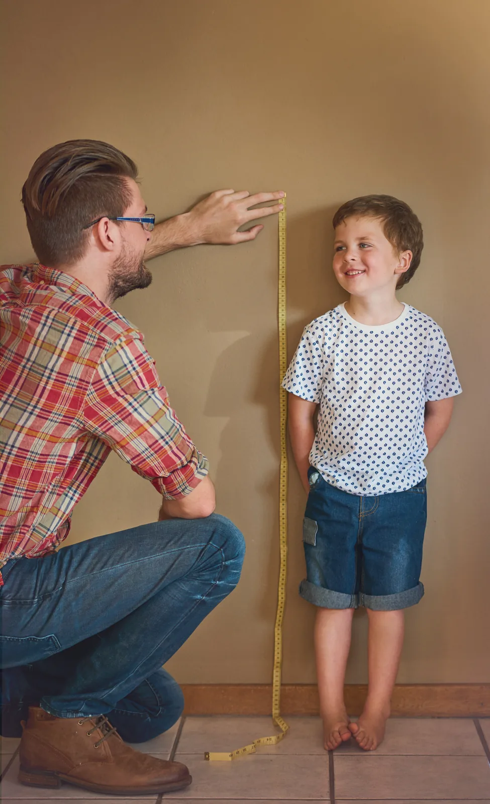 Father measuring his son's height against a wall